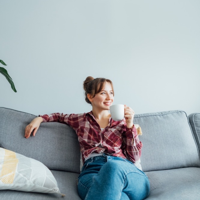 Woman sitting in couch and drinking coffee